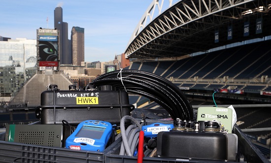A crate full of seismic equipment sits in Century Link field with the empty stadium and the Seattle skyline behind it.